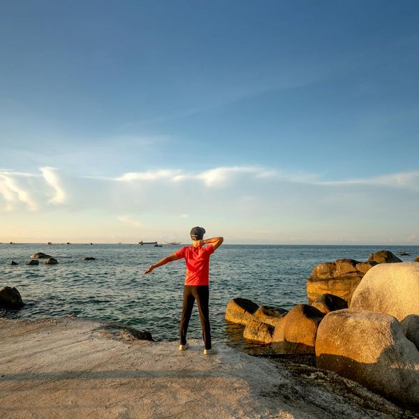 Silhouette of a man stretching at sunrise, symbolizing energy and well-being.